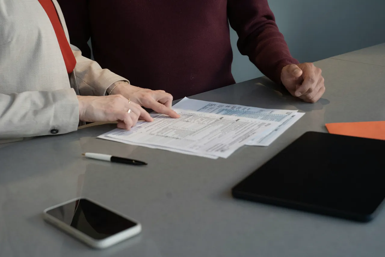 Two people checking structured records and source documents