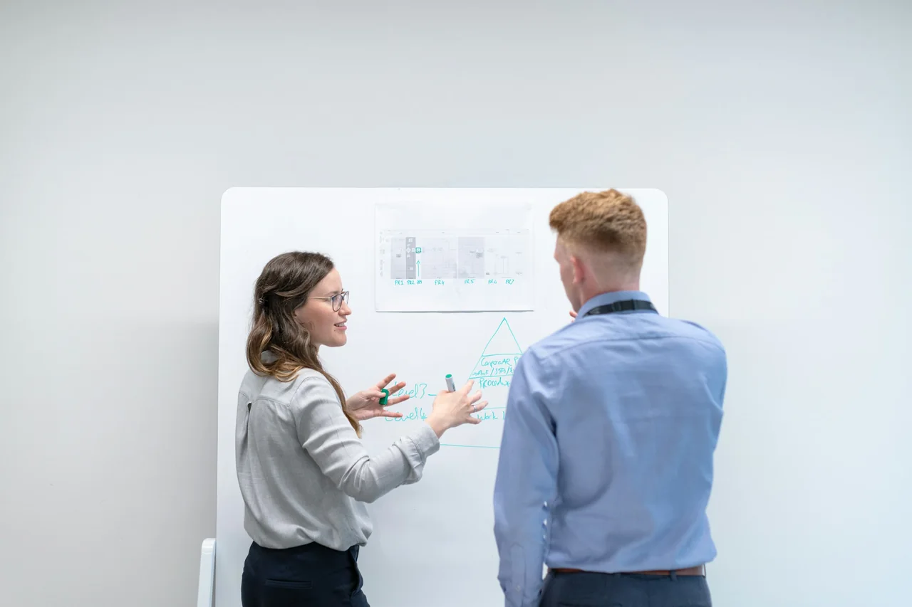 Two engineers reviewing technical information at a whiteboard